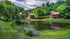 Una propiedad tranquila junto al lago con cabañas de madera, un estanque y abundante vegetación.