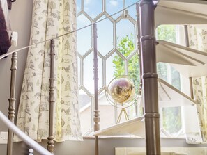 A room with a hexagonal window, curtains with animal prints, and a globe on a tripod stand.