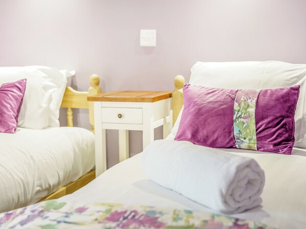 A twin room with two beds, a wooden nightstand, and a white wall.