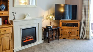 Una sala de estar con chimenea, televisor, muebles de madera y un espejo.