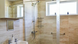 Un baño moderno con ducha de vidrio, lavamanos y ventana.