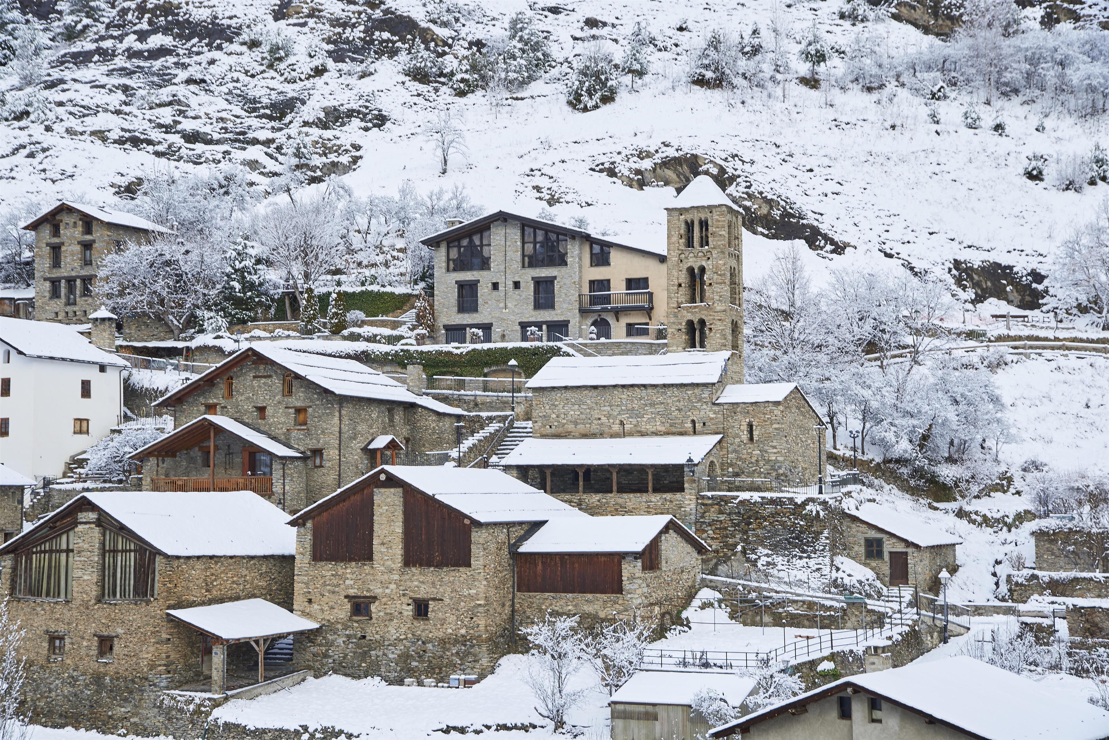 A snow-covered village with stone buildings, including a prominent tower.