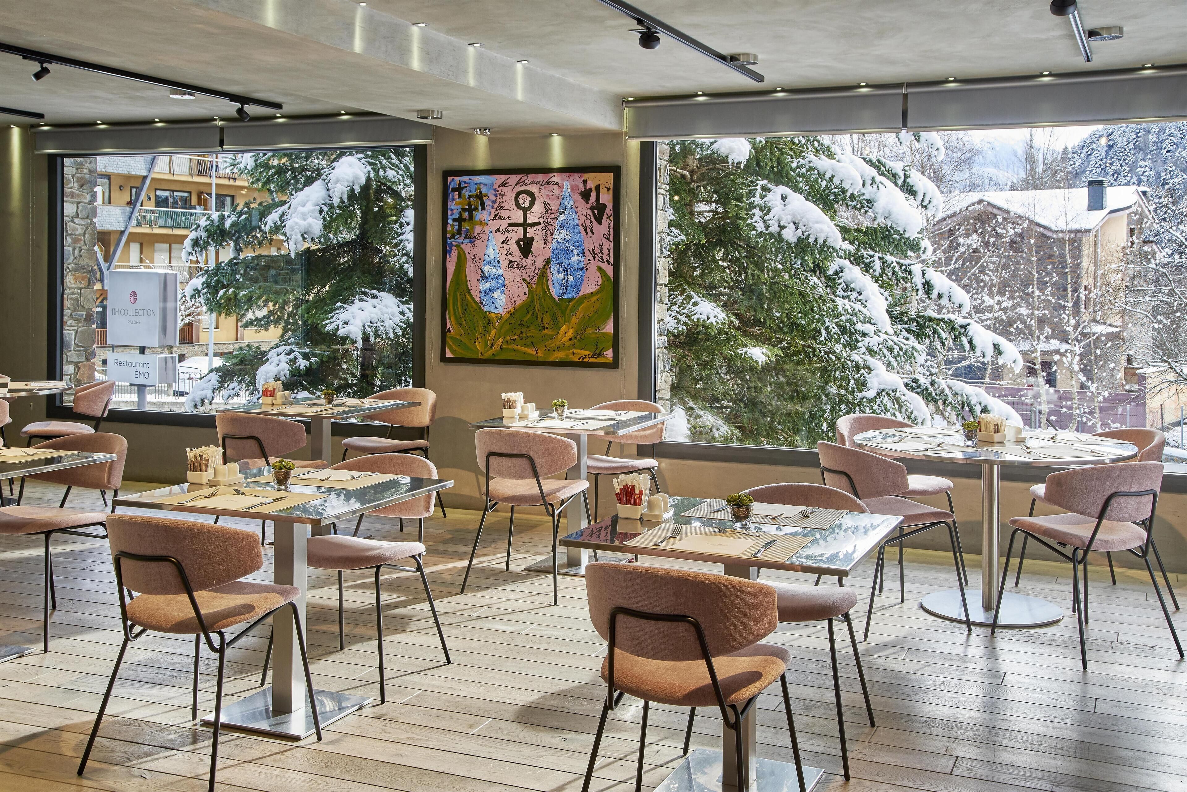 A restaurant with tables and chairs, large windows, and a painting on the wall.
