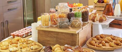 A buffet with various food items including pastries, fruits, and condiments.