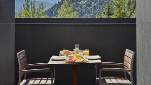 A table set with breakfast items, two chairs, and a view of a mountainous landscape. - NH Collection Andorra Palome (Arinsal)