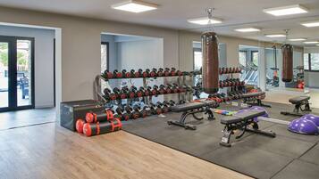 A gym with weightlifting equipment, cardio machines, and a punching bag.