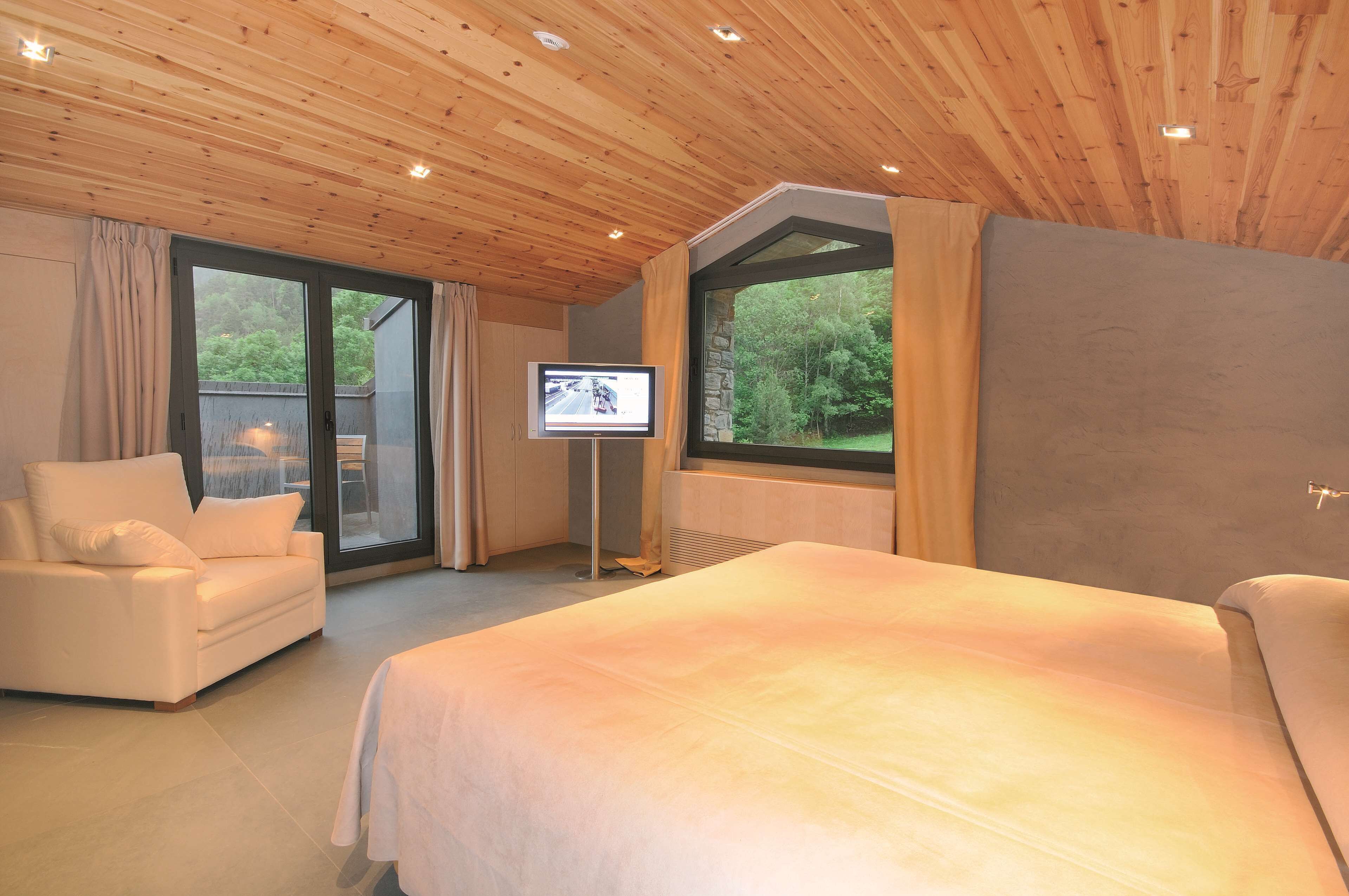 A bedroom with a large bed, a sofa, and a TV.