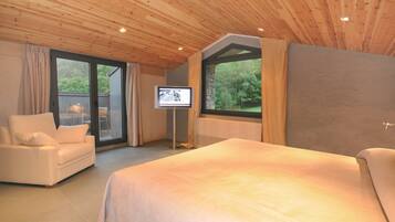 A bedroom with a large bed, a sofa, and a TV.