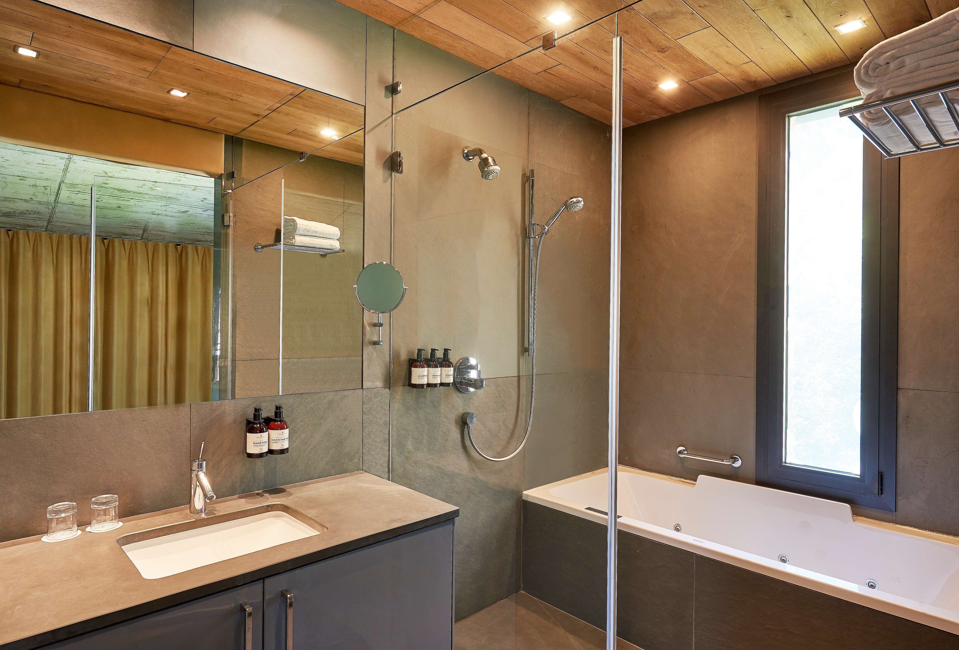 Une salle de bain moderne avec une douche à parois de verre, un grand miroir, un meuble-lavabo et une baignoire.