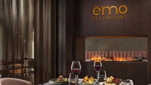 A restaurant setting with a table set for dining, a fire feature in the background, and the restaurant's name displayed on the wall. - NH Collection Andorra Palome (Arinsal)