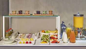 Un bufé con diferentes opciones de comida, entre ellas frutas, postres y bebidas.