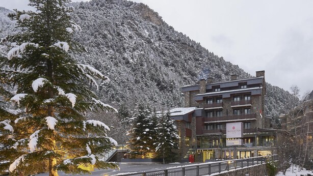 A snow-covered mountain with a building featuring balconies and a restaurant sign. - NH Collection Andorra Palome (Arinsal)