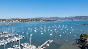 Un puerto deportivo con numerosas embarcaciones amarradas, un cielo azul despejado y un horizonte con edificios.