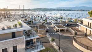 Un puerto deportivo con barcos, una carretera y edificios modernos con balcones y terrazas.