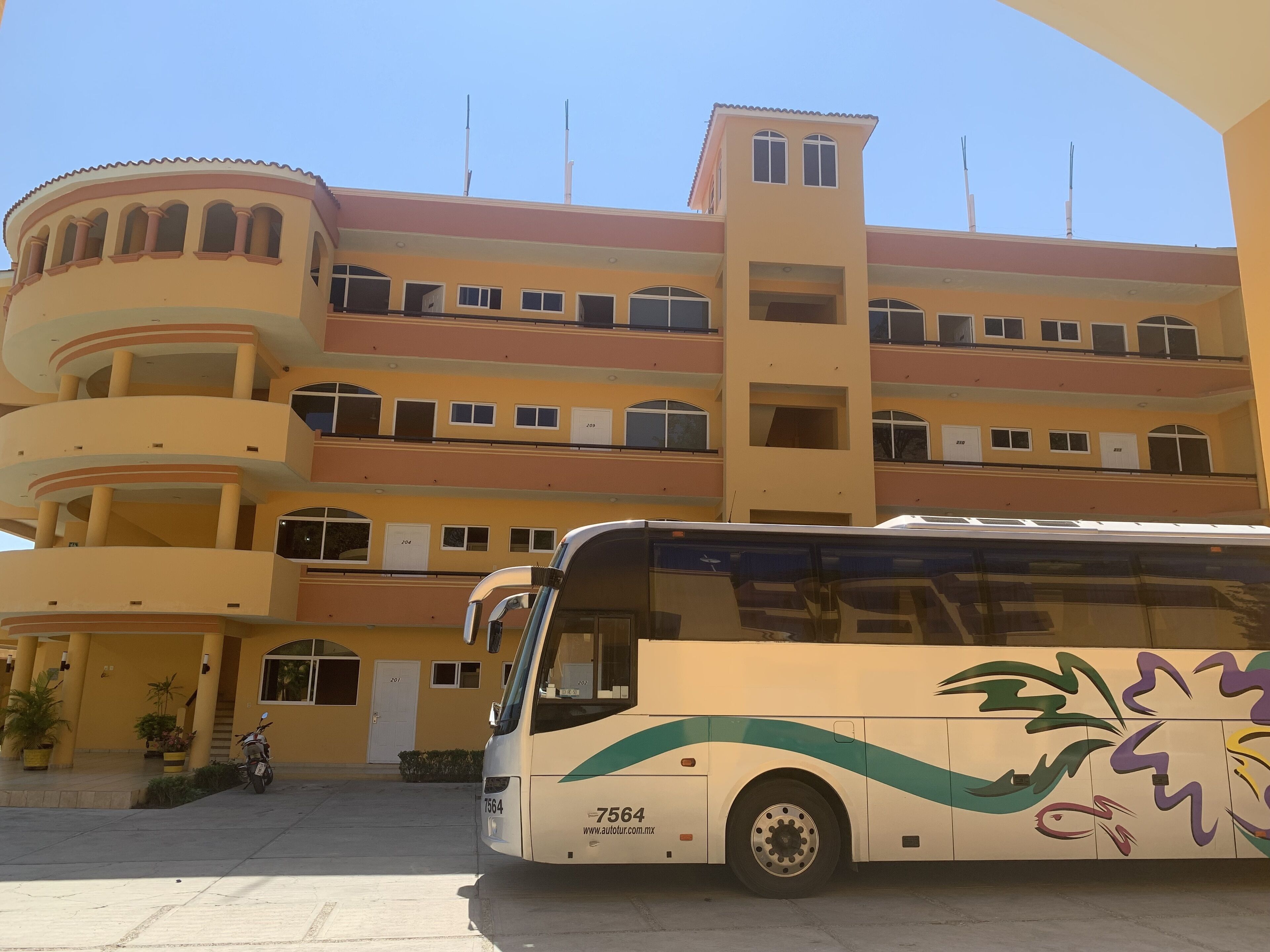 Un immeuble à plusieurs étages, doté de balcons, devant lequel est garé un autobus.