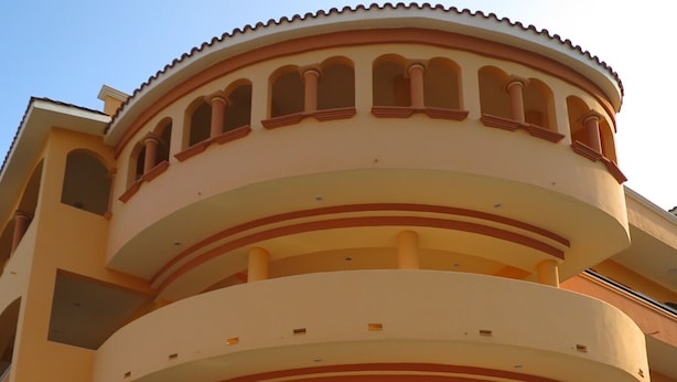 A multi-story building with a curved facade, balconies, and a central courtyard with seating and potted plants. - BONADAY HOTEL (Ometepec)