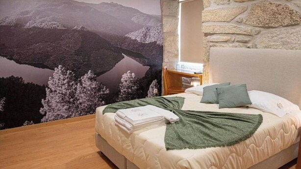 A bedroom with a bed, pillows, a nightstand, and a view of mountains and a lake. - The Village House - Mallus (Carrazeda de Anciães)