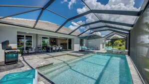 Une piscine intérieure à l’eau claire, entourée d’un patio couvert aménagé avec des sièges et un barbecue.