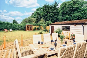 Enjoy al fresco dining in a serene garden setting with a deck and lush greenery.