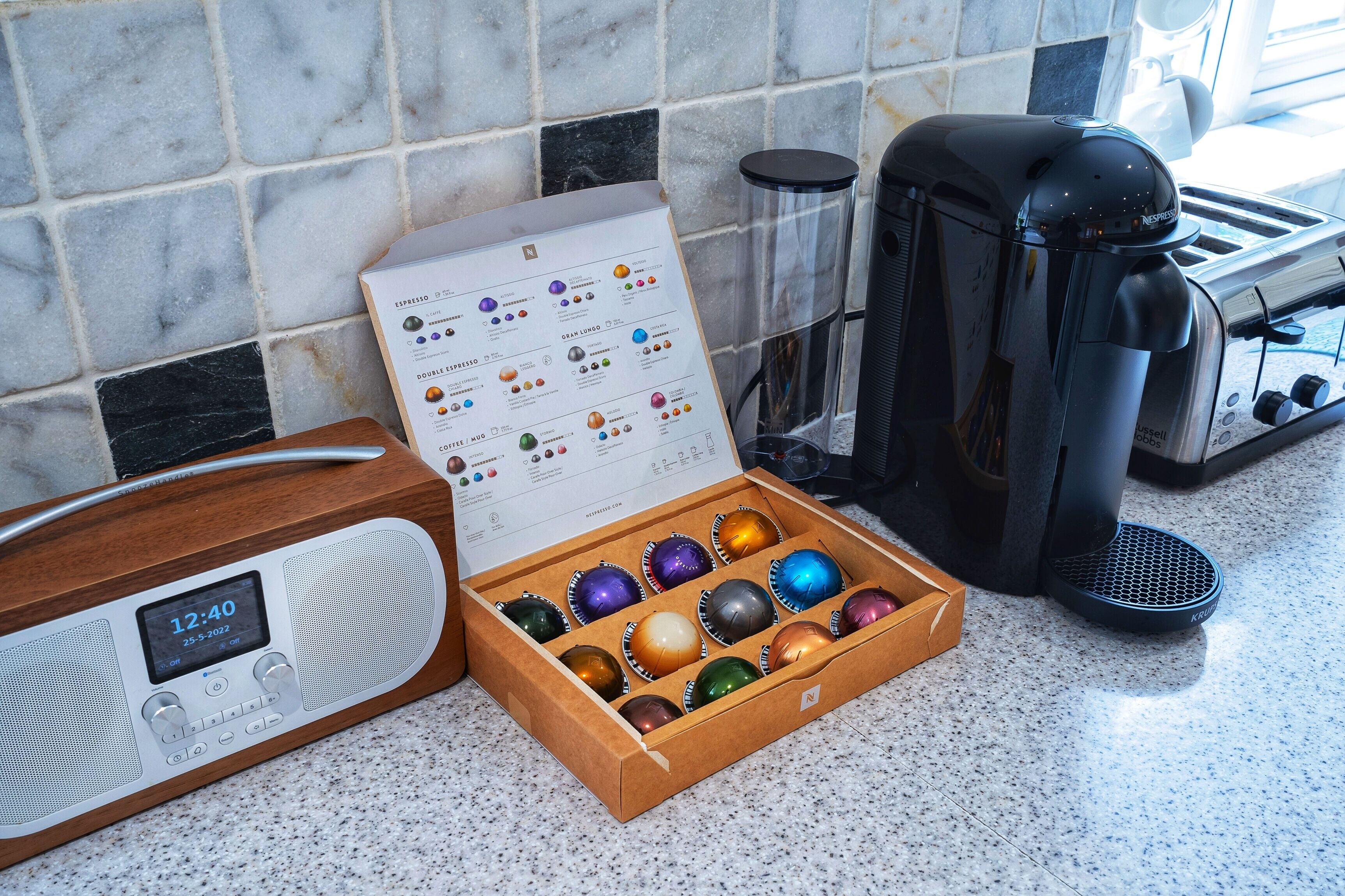 A kitchen with a coffee maker, a toaster, and a box of coffee pods.