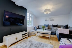 Relax in this stylish living room with a large flat-screen TV, console table, and comfortable sofa.