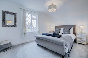 Cozy retreat with a large bed, bedside table, dresser, and mirror.