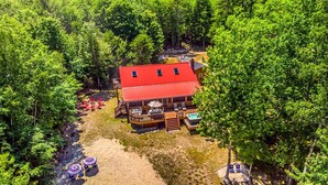 A lodge with a red roof, wooden deck, and outdoor seating area.