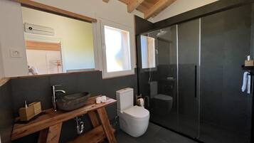 A modern bathroom with a wooden vanity, a white toilet, and a glass shower enclosure.