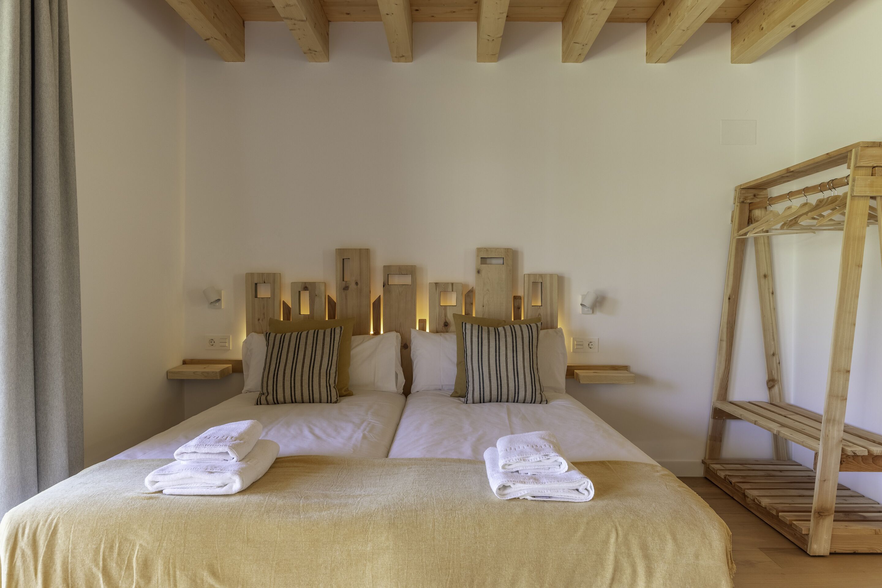 Una cama doble con dos almohadas, un cabecero de madera y una mesita de noche de madera.