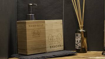 Een houten zeepdispenser met pomp, een bamboe re diffuser en een fles met een bloemmotief.