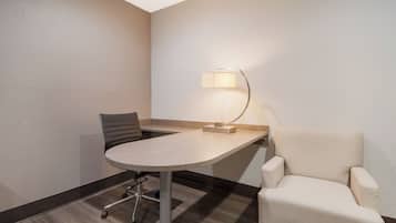 A conference room with a table, chairs, a lamp, and a carpeted floor.