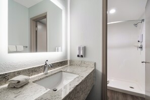 A bathroom with a marble sink, a large mirror, a shower, and a toilet.