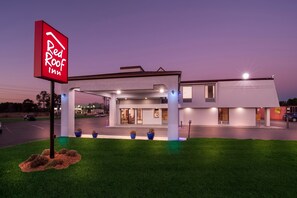 Een Red Roof Inn met een modern ontwerp, inclusief een overdekte parkeerplaats en een goed verlichte entree.