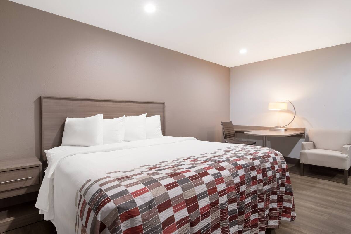 A hotel room with a large bed, a desk, and a chair.