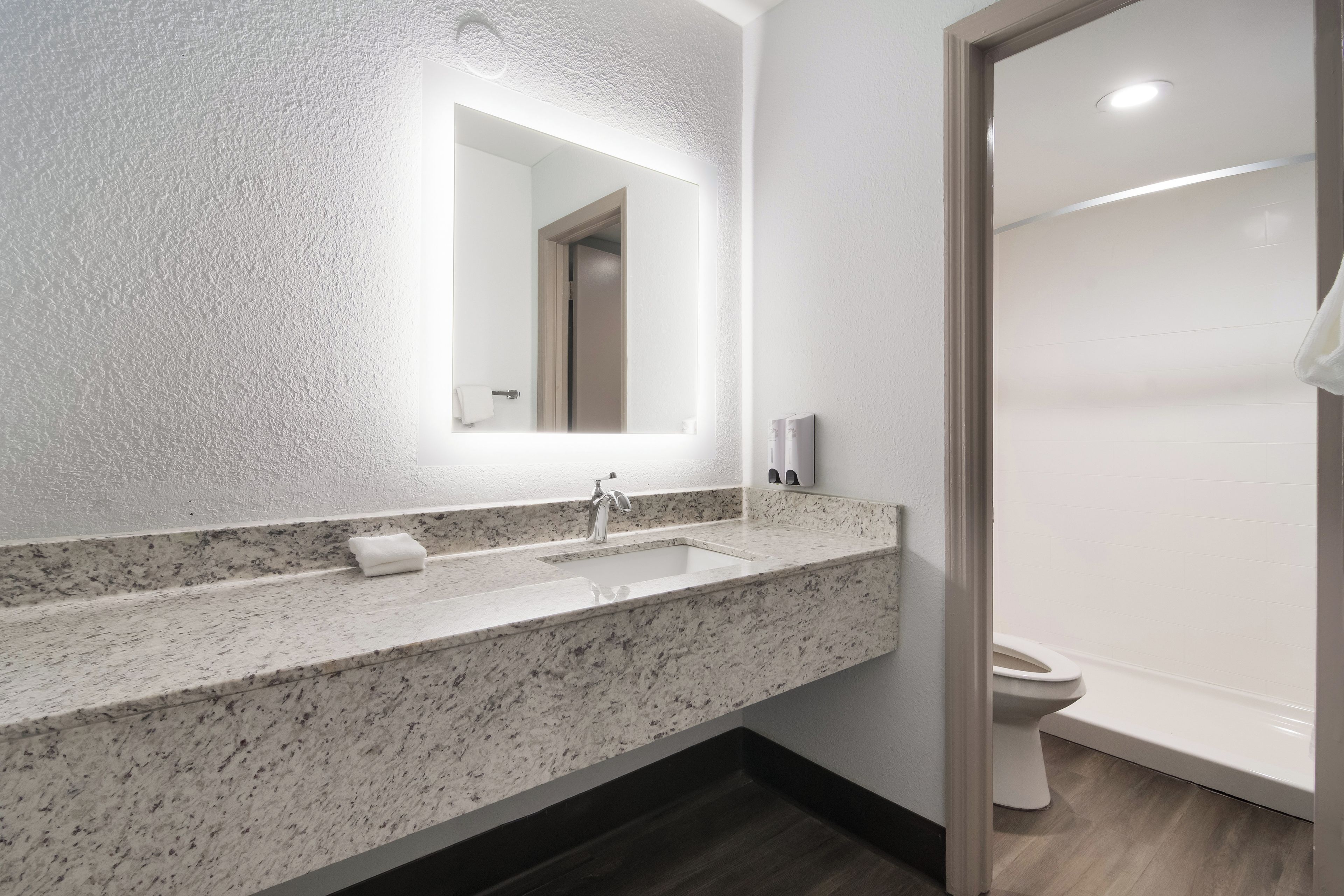 Un baño moderno con lavamanos de granito, un espejo y un inodoro.