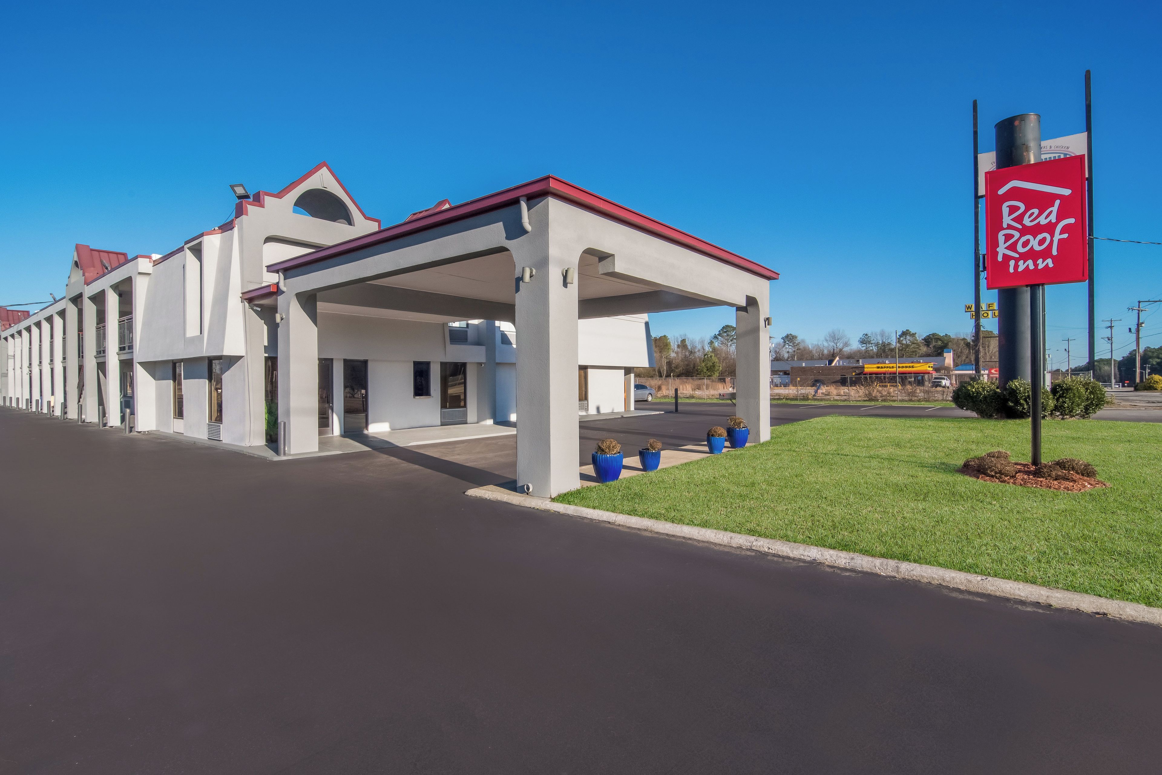 A Red Roof Inn with a covered parking area and a clear sky.