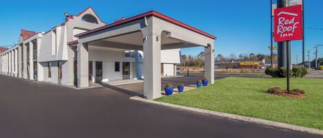 A Red Roof Inn with a covered parking area and a clear sky.