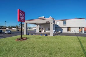 A Red Roof Inn with a covered parking area and a building with a flat roof.
