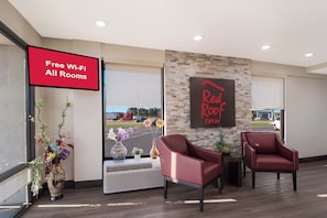 A hotel lobby with a 'Free Wi-Fi All Rooms' sign, a 'Red Roof Inn' sign, and two red armchairs. - Red Roof Inn Rocky Mount - Battleboro (Battleboro)