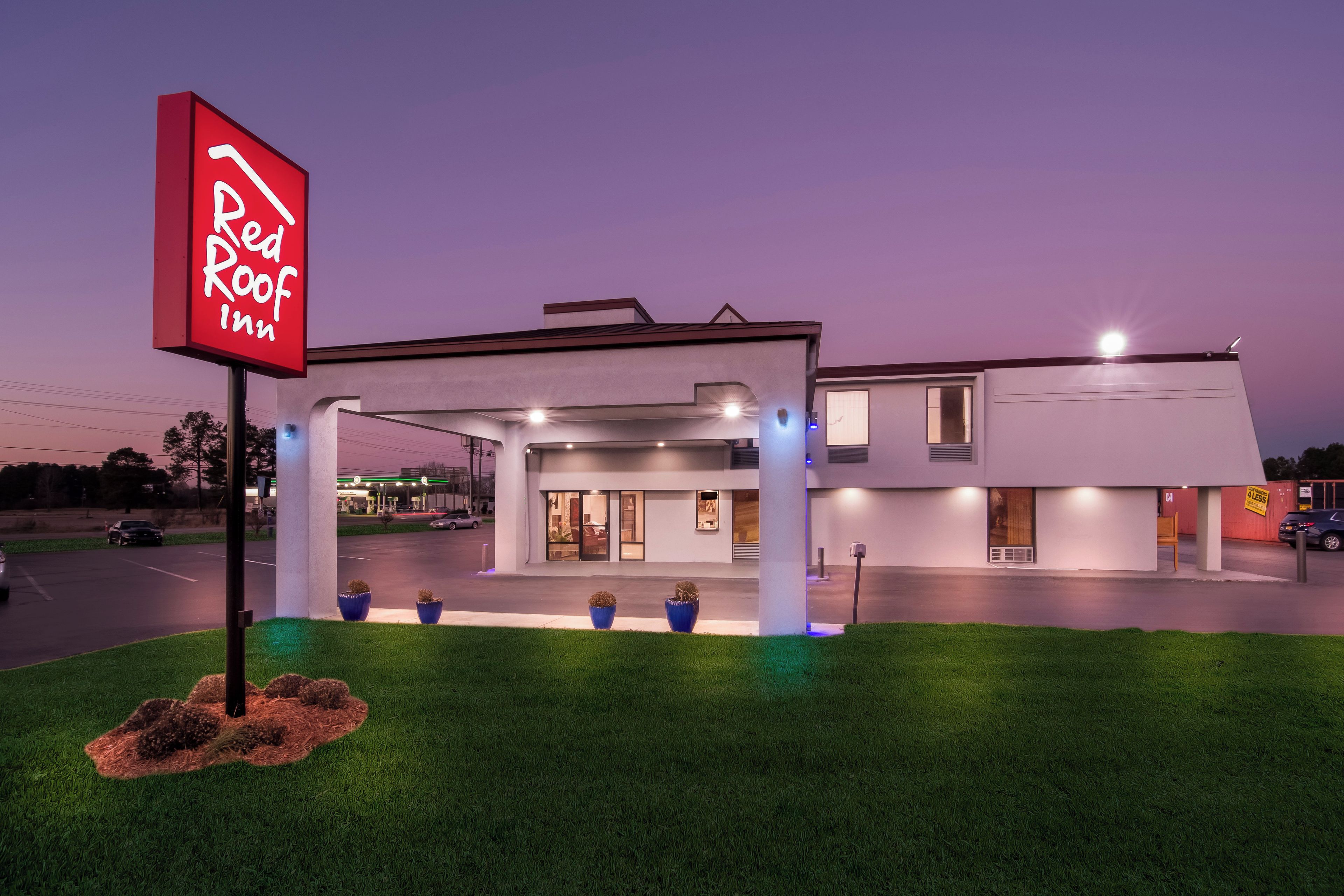 Un hôtel Red Roof Inn au design moderne, doté d’un parking couvert et d’une entrée bien éclairée.