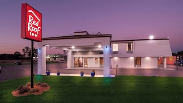 Un hôtel Red Roof Inn au design moderne, doté d’un parking couvert et d’une entrée bien éclairée.