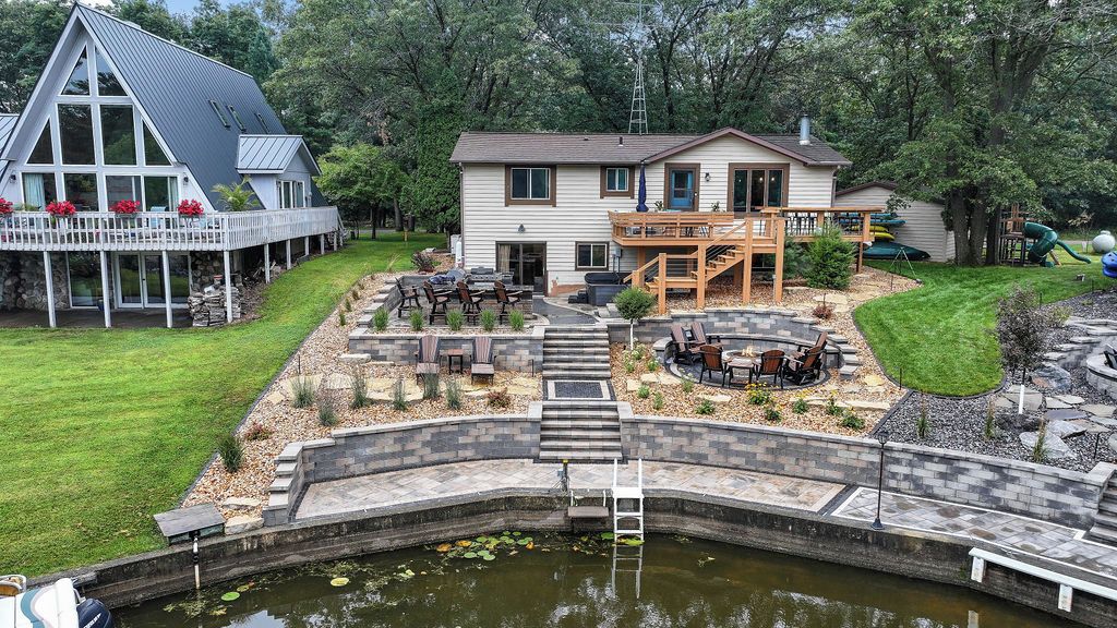 Ein Haus mit Terrasse, Sitzbereich im Freien und einem Teich.