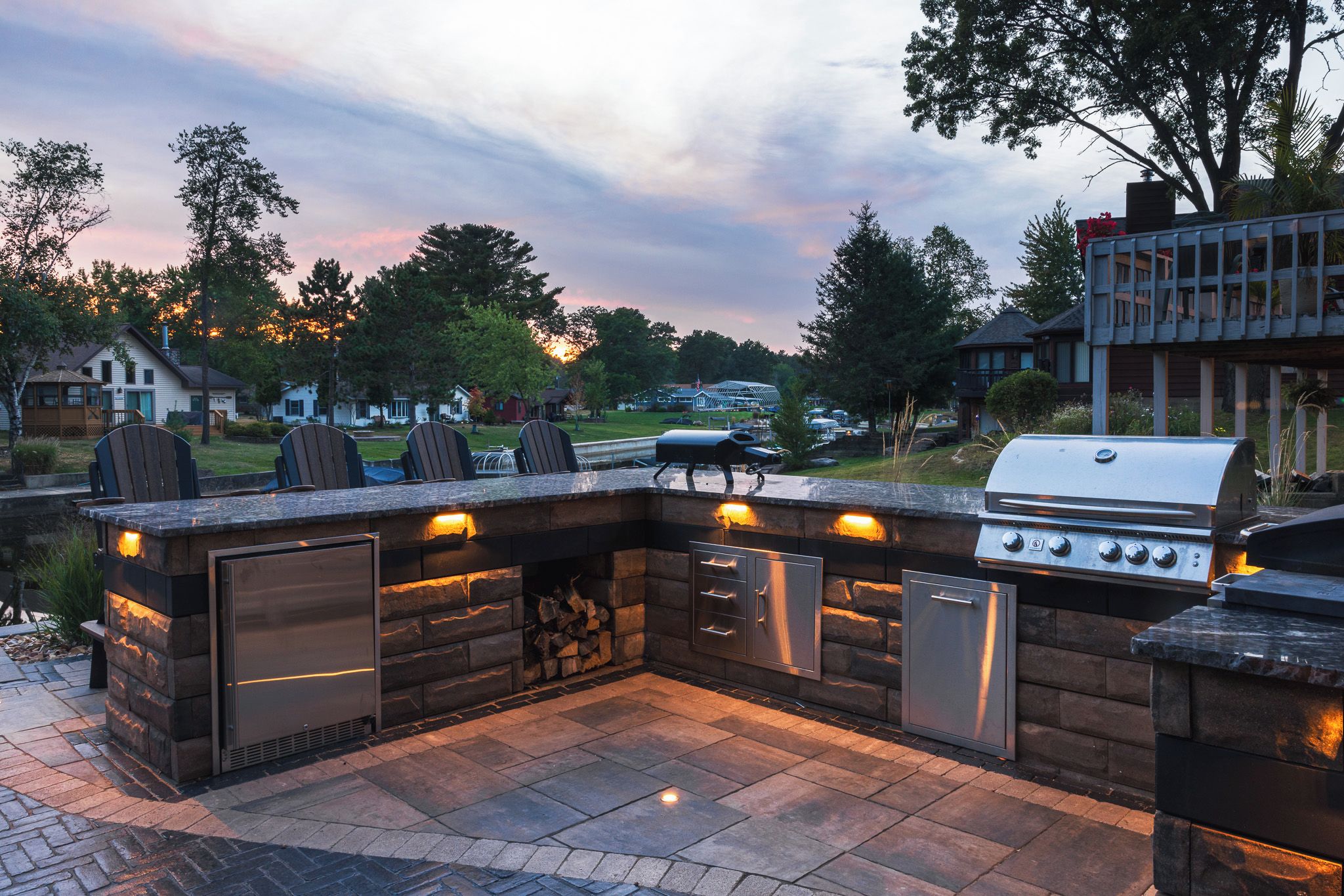 Cocina exterior con parrilla, zona de estar y almacenamiento integrado.
