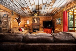 Cozy cabin interior with a leather sofa, fireplace, and mounted deer head.