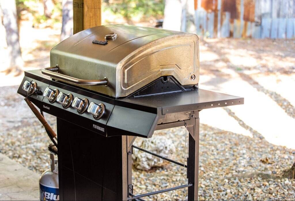 A portable grill with a control panel and a lid, placed on a metal stand.