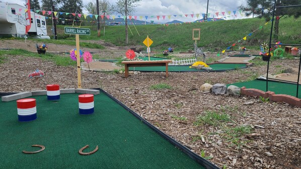 Un campo de mini golf con obstáculos coloridos y un cartel que dice 'Barrel Racing Dr'.
