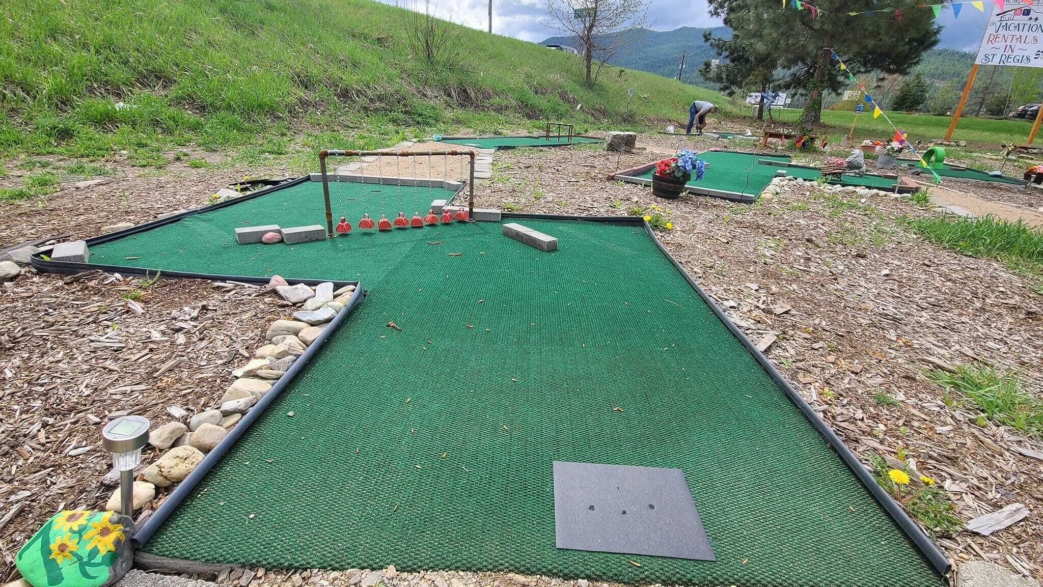 Un camp de mini-golf amb diverses bases de gespa per fer els cops, un sistema de retorn de pilotes metàl·lic i una taronja de pedra.