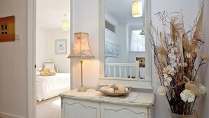 A bedroom with a bed, a bedside lamp, a dresser, and a mirror.