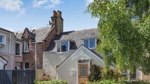 A residential house with a sloped roof, a chimney, a small window, and a door. - Willow Cottage - Uk39244 (Inverness)