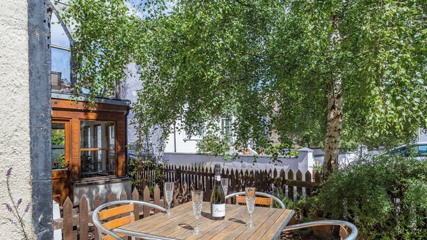 An outdoor wooden table with metal chairs, a bottle of wine, and a glass. - Willow Cottage - Uk39244 (Inverness)
